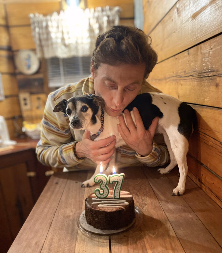 Dominick holding a small dog beside a birthday cake