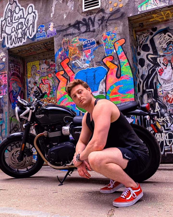 Dominick training with a barbell in front of a graffiti wall